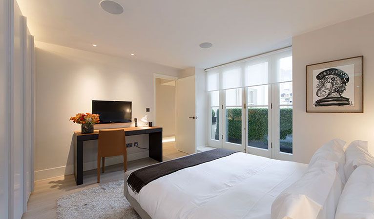 Bedroom with French doors, opening to balcony in Kensington with bespoke Italian wardrobes & intelligent mood lighting